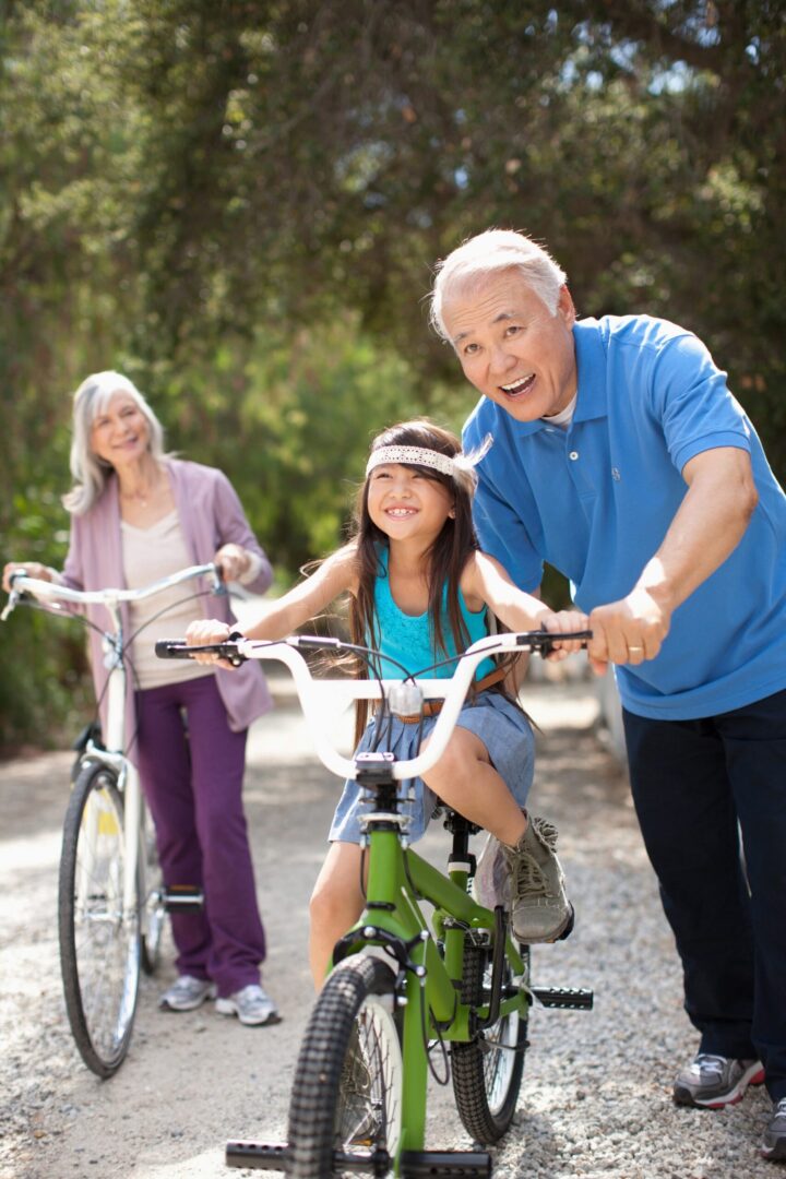 Older adults helping child learn to ride bike