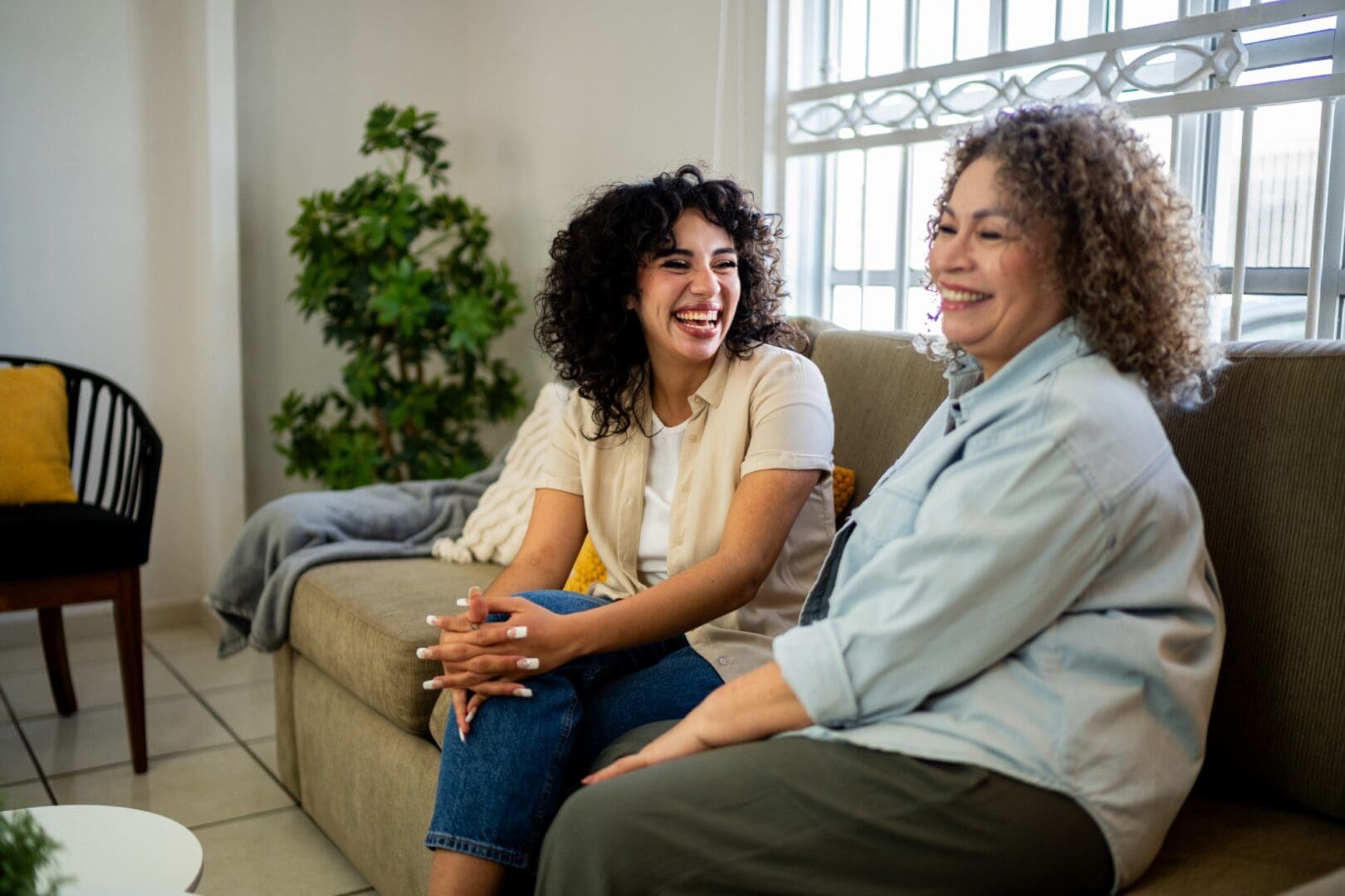 Two women laughing on a sofa