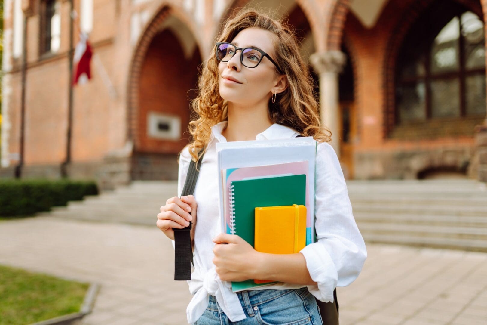Student holding books outside a university building