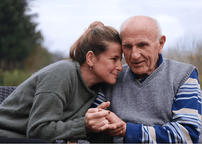 Woman comforting elderly man, holding hands