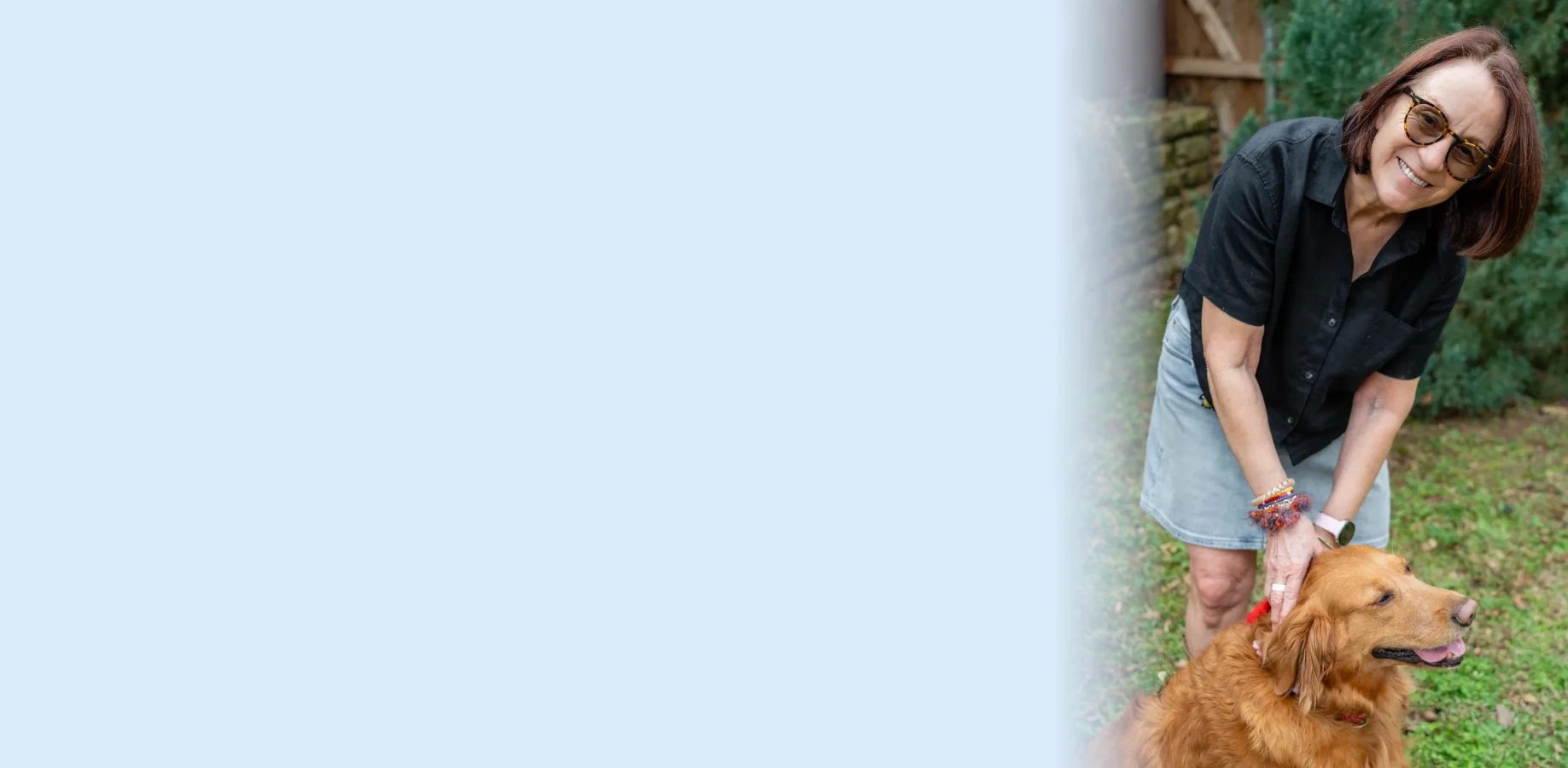 Smiling woman leaning to pet golden retriever